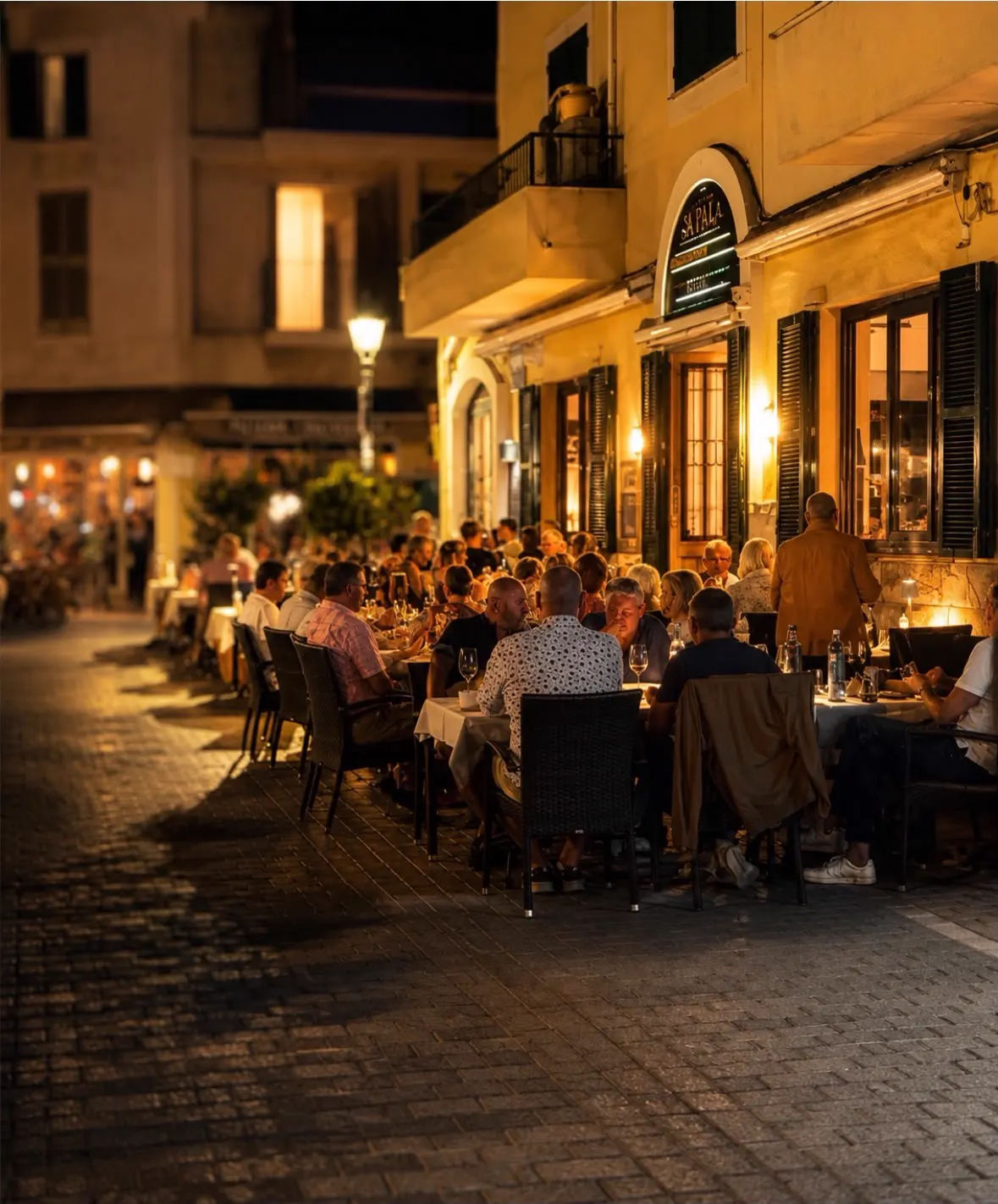 Warm evening in the pedestrian streets of Port d'Andratx with full outside tables